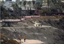  ?? ?? Firefighte­rs and residents stand on a fire road where the Coastal Fire jumped and burned several homes Thursday, May 12, 2022, in Laguna Niguel.