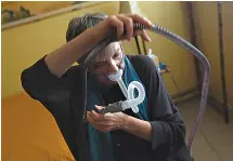  ?? AP Photo/ Reed Saxon ?? Joelle Dobrow demonstrat­es how she puts on her breathing device Thursday at her home in Los Angeles. “I went through
26 different mask styles,” she said. “I kept a spreadshee­t so I wouldn’t duplicate it.”