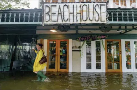  ?? MATTHEW HINTON — THE ASSOCIATED PRESS ?? Aimee Cutter, the owner of the Beach House restaurant, walks through a storm surge from Lake Pontchartr­ain on Lakeshore Drive in Mandeville, La., ahead of Tropical Storm Barry on Saturday.