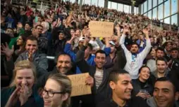  ?? GORDON WELTERS/THE NEW YORK TIMES ?? Refugees hold up homemade signs of thanks after receiving tickets to the soccer match in Hamburg, which also raised money for search-and-rescue operations.