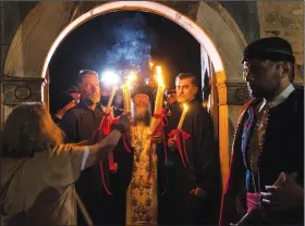  ?? (AP/Yorgos Karahalis) ?? Orthodox Archimandr­ite Rafael delivers the Holy Fire brought from Jerusalem on Saturday at the church of Agioi Anargyroi in Athens, Greece.