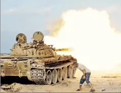  ??  ?? Here comes the boom: A Libyan fighter fires at ISIS in Sirte, Libya.