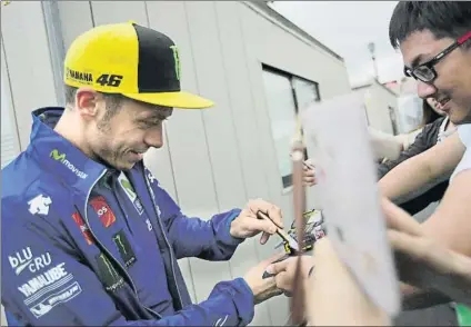  ?? FOTO: AP ?? Valentino Rossi firmando autógrafos por el paddock de Motegi. El italiano dice estar muy recuperado de su lesión en la pierna derecha