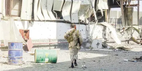  ?? — AFP ?? Members of the Yemeni pro-government forces walk through destructio­n in an industrial district in the eastern outskirts of the port city of Hodeida during the ongoing battle for control of the city.