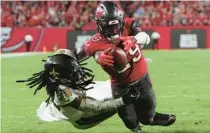  ?? MARK LOMOGLIO/AP ?? Bucs running back Rachaad White dives into the end zone for a touchdown as Saints linebacker Demario Davis can’t stop White’s forward progress.