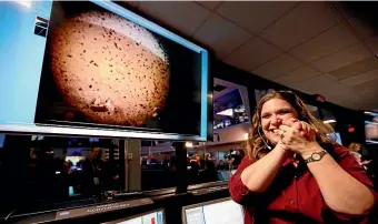  ?? AP ?? An engineer celebrates in the space flight operation facility at Nasa’s Jet Propulsion Laboratory in Pasadena, California, next to an image of Mars sent from the InSight lander shortly after it landed on Mars.