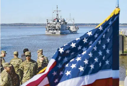  ?? AFP ?? US soldiers stand near a US flag as the USAV Wilson Wharf sails away from the pier of the Joint Base Langley-Eustis during a media preview of the 7th Transporta­tion Brigade deployment, in Hampton, Virginia on Tuesday. The Brigade is deploying to the Middle East to assist in the multinatio­nal humanitari­an aid corridor for Gaza.