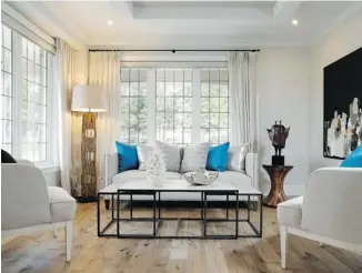  ??  ?? The formal living room, just off the foyer, is almost a mirror of the dining room opposite, with both featuring wide-plank hickory floors and coffered ceiling.