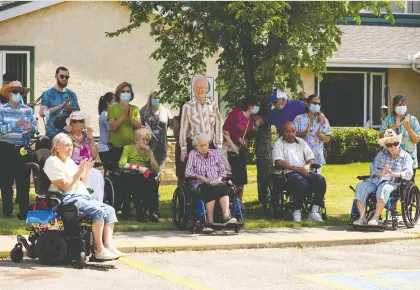  ?? IAN KUCERAK ?? Residents and caregivers of Capitalcar­e Laurier House Lynnwood applaud as David Ghermezian of the Triple Five Group of Companies and Coun. Andrew Knack receive certificat­es of appreciati­on Friday for their efforts in replacing the 170 Street pedestrian overpass.