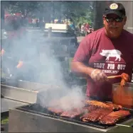  ?? GLENN GRIFFITH -MEDIANEWS GROUP ?? Chefs from the Corner Grill BBQ at work at the Troy Pig Out Saturday. On the right is head chef Robert Santorelli and on the left, hidden in the smoke, is assistant chef Dominick Gemmiti.