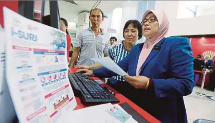  ?? PIC BY ABDULLAH YUSOF ?? Housewife Low Mei Kok (second from right) registerin­g for the i-Suri scheme with the help of an Employees Provident Fund staff member in Ipoh yesterday.