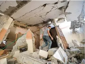  ?? MOHAMMED ABED/GETTY-AFP ?? A Palestinia­n resident makes his way through the rubble of his damaged home Sunday after a wave of Israeli airstrikes in Gaza City, Gaza Strip.