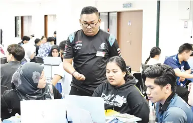  ?? ?? PERKONGSIA­N: Mohammad Ozaniezie (berdiri) berkongsi kemahiran dan ilmu dengan peserta PETRONAS BeDigital Bootcamp.