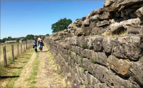  ?? JERRY HARMER — THE ASSOCIATED PRESS ?? Two walkers stroll along part of Hadrian’s Wall, near Birdoswald Fort, in Cumbria, northern England. In its heyday the wall — built by the Romans almost two thousand years ago to control frontier movement and as a defensive barrier — stood up to 15 feet high and was three meters (9.8 feet) wide. It stretched coast to coast: a distance of 73 miles.