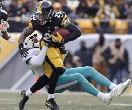  ?? DON WRIGHT — THE ASSOCIATED PRESS ?? Pittsburgh Steelers running back Le’Veon Bell (26) runs through a tackle by Miami Dolphins free safety Bacarri Rambo during the first half of an AFC wild-card NFL football game in Pittsburgh, Sunday.