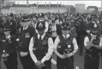  ?? DAN KITWOOD, GETTY IMAGES ?? Police officers hold roses on Westminste­r Bridge as they attend a vigil to remember the victims of last week’s Westminste­r terrorist attack on Wednesday in London, England.