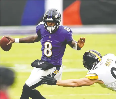  ?? MITCHELL LAYTON/ USA TODAY SPORTS ?? Baltimore QB Lamar Jackson, seen avoiding Steelers linebacker T.J. Watt when the two teams met on Nov. 1, is the latest member of the Ravens to test positive for COVID-19. A dozen Ravens players were placed on the Covid-19/reserve list this week.