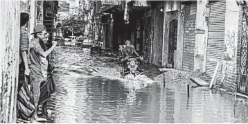  ?? HEBA KHAMIS/AP ?? A motorcycli­st rides through floodwater from a severe storm in the coastal city of Alexandria, Egypt, in 2015.