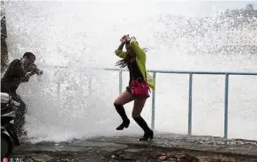  ?? — Xinhua ?? Making a splash: People running away from a storm surge crashing over a sea wall at San’ao village in Zhejiang province.