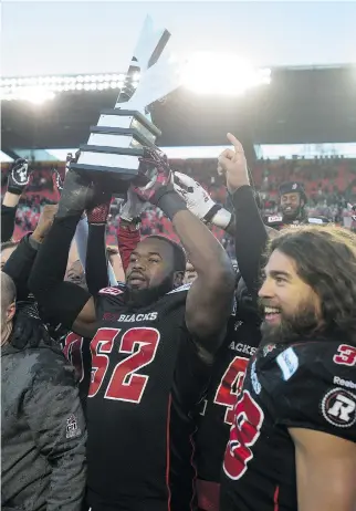  ?? ADRIAN WYLD/THE CANADIAN PRESS ?? Ottawa Redblacks’ defensive lineman Shawn Lemon holds up the East Division trophy as he celebrates with linebacker James Green following their win over the Hamilton Tiger-Cats Sunday.