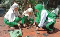  ?? PUJI TYAS/JAWA POS ?? MANFAATKAN LAHAN: Siswa dan guru SD Al Irsyad menanam terong, cabai, dan tomat di sekolah kemarin.