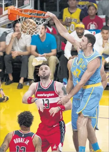  ?? Kyusung Gong Associated Press ?? WASHINGTON CENTER Marcin Gortat watches helplessly as the Lakers’ Larry Nance Jr. completes a dunk during the first half of Wednesday night’s game. Nance finished with 18 points and 10 rebounds.