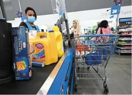  ?? — AFP ?? More customers: A cashier scans items at a Walmart store in California. In the United States, its online grocery market share, which includes pickup and delivery services, rose to 55% in the monthofjun­efrom 52% in March.