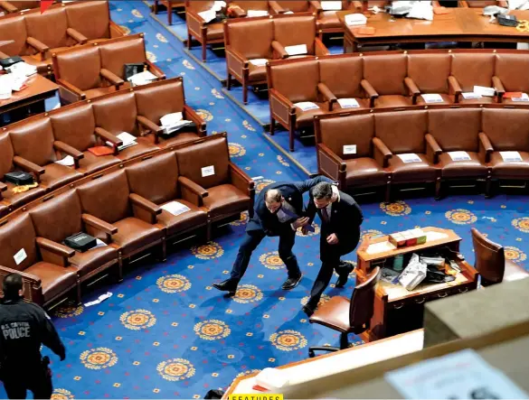  ??  ?? THIS IS AMERICA
Republican Pennsylvan­ia Congressma­n Dan Meuser (right) being led to safety across the floor of the U.S. House of Representa­tives by unidentifi­ed law enforcment officers.