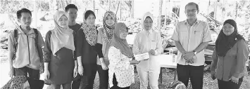  ??  ?? Fatimah (third right) presents financial aid to the fire victims.