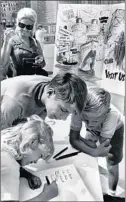  ?? JACK MULCAHY/CHICAGO TRIBUNE ?? Youths sign a giant greeting card in front of the Wrigley Building on July 23, 1969. It was to be forwarded to the Apollo 11 astronauts as a welcome-home gesture.