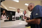  ?? GERALD HERBERT ?? Alex Domino, right, the first person to receive medical marijuana in Louisiana, purchases his dose at Capitol Wellness Solutions, in Baton Rouge, La., Tuesday.