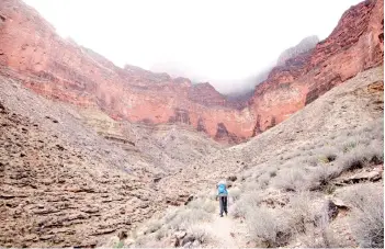  ?? — The Washington Post photos ?? John Briley’s son Kai hikes along the Tonto Trail on the third day of their early March backpackin­g trip as mist spills off the South Rim of the Grand Canyon far above.