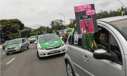  ??  ?? A woman holds up a sign reading ‘Brazilian lives matter. Out Bolsonaro!’ during a motorcade in São Paulo. Photograph: Amanda Perobelli/Reuters