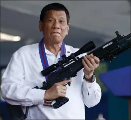  ?? THE ASSOCIATED PRESS ?? Philippine President Rodrigo Duterte jokes as he holds an Israeli-made Galil rifle in Quezon city, Philippine­s. 2018. Duterte is under fire for his anti-drug crackdown.