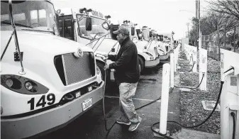  ?? Max Whittaker / New York Times ?? Paul Harrison, who drives for the Twin Rivers School District, plugs in his electric school bus after morning pickup in Sacramento, Calif. The district uses 25 electric school buses built by Lion Electric.