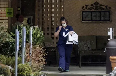  ?? ASSOCIATED PRESS ?? A worker at the Life Care Center in Kirkland, Wash., near Seattle, wears a mask as she leaves the building, March 2. Several of the people who have died in Washington state from the COVID-19coronavi­rus were tied to the long-term care facility, where dozens of residents were sick.