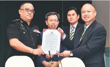  ?? — Photo by Tan SW ?? Chan (right) presents the signed pledge to Zulhairy (left), witnessed by Dr Sim (second left) and Tay.