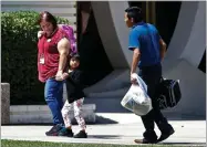  ?? AP FILE PHOTO BY MATT YORK ?? In this July 26, photo, a child holds the hand of a Lutheran Social Services worker as she looks back to a man as they arrive at Lutheran Social Services in Phoenix.