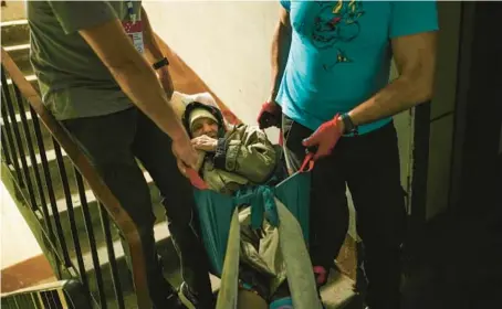  ?? FRANCISCO SECO/AP ?? Volunteers with the Vostok SOS charitable organizati­on evacuate an elderly woman from her home May 26 in Kramatorsk, eastern Ukraine.