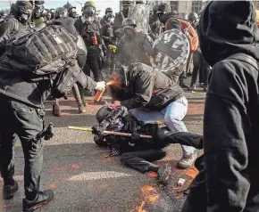  ?? DAVID RYDER/GETTY IMAGES ?? A counterpro­tester sprays a Trump supporter with bear mace during political clashes Saturday in Olympia, Wash., as far-right and far-left groups squared off near the Washington State Capitol.