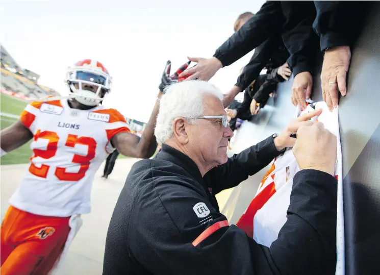  ?? — THE CANADIAN PRESS FILES ?? B.C. Lions head coach Wally Buono signs a souvenir jersey for a fan after a September game against the Tiger-Cats in Hamilton.