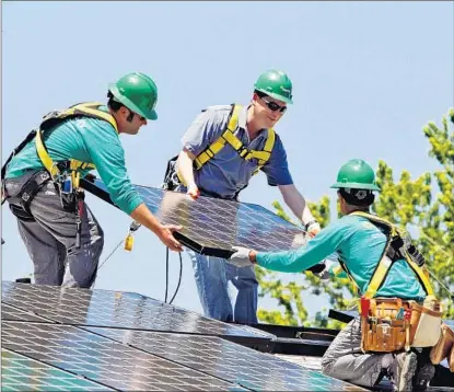  ?? Ed Andrieski
Associated Press ?? SEN. MICHAEL BENNET (D-Colo.), center, helps as SolarCity employees Jarret Esposito, left, and Jake Torwatzky install rooftop solar panels on a south Denver home in 2010. San Mateo, Calif.-based SolarCity operates in 19 states.