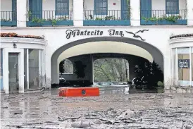  ?? [DANIEL DREIFUSS/THE ASSOCIATED PRESS] ?? Debris and mud cover the entrance of the Montecito Inn after heavy rain brought flash flooding and mudslides to the area in Montecito, Calif. Buildings were swept from their foundation­s as heavy rain sent mud and boulders sliding down hills.