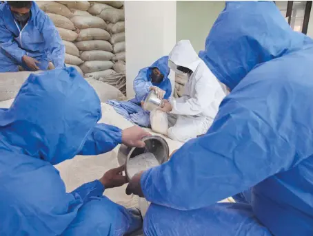  ?? AP ?? Kashmiri men employed by government pack wheat flour for distributi­on among needy people inside a temporary storage in Srinagar on Tuesday.