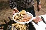  ?? TIMES BRETT CARLSEN PHOTOS/THE NEW YORK ?? Allan Benton presents the final dish of ham, bacon, potatoes with ramps and cornbread in the Cherokee National Forest in Tennessee. “Lots of people around here like to eat their ramps with ham and eggs,” he said. “I prefer the potatoes.”