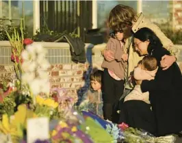  ?? ASHLEY LANDIS/AP ?? A family gathers at a memorial near the Star Ballroom Dance Studio in Monterey Park, Calif. A gunman killed multiple people at the studio.