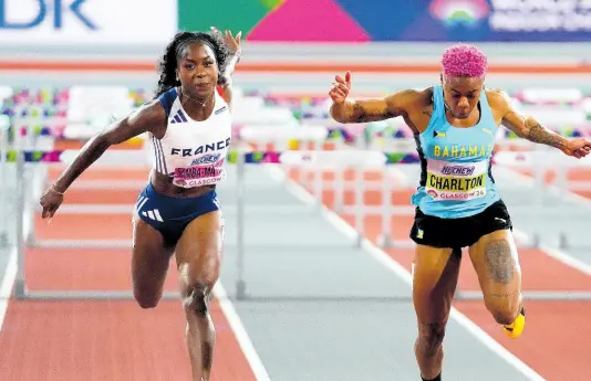  ?? AP ?? Devynne Charlton (right) of The Bahamas crosses the finish line to win the gold medal in the 60-metre hurdles ahead of second-place Cyrena SambaMayel­a, of France at the World Athletics Indoor Championsh­ips in Glasgow, Scotland, yesterday. Charlton won the event in a world record 7.65 seconds. Samba-Mayela was second in 7.74.