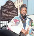  ?? EBONY COX / MILWAUKEE JOURNAL SENTINEL, MILWAUKEE JOURNAL SENTINEL FILES ?? ABOVE: Tyrone Macklee Randle stands in front of a historical marker designatin­g the spot of the 1861 lynching of George Marshall Clark at 220 E. Buffalo St. in Milwaukee’s Third Ward on Oct. 11. He led the efforts to get a headstone for Clark’s unmarked grave in Forest Home Cemetery. FAR RIGHT: James Cameron poses in front of a photograph of a lynching on display at America’s Black Holocaust Museum in this 1988 photo.