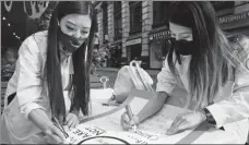  ?? BEBETO MATTHEWS / AP LIAO PAN / CHINA NEWS SERVICE Right: ?? Left: Students from New York University celebrate their graduation on May 19. Michelle Lee, left, a doctor, and Ida Chen, an assistant physician student, prepare posters on April 24 in New York’s Chinatown to protest anti-Asian hatred.