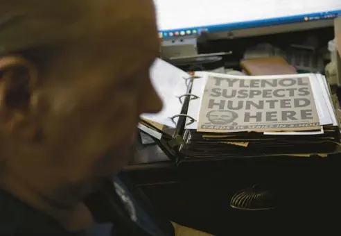  ?? LISA KRANTZ/FOR THE CHICAGO TRIBUNE ?? Retired FBI agent Tom Ellis looks at an album featuring photos and newspaper clippings about the Tylenol case, including mug shots of James Lewis.